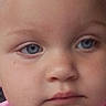 child, toddler, face, blue_eyes, skin, expression, close_up, pink_shirt, person, portrait, innocence, baby, young, human, head, eyebrow, nose, lip, cheek, eyelid