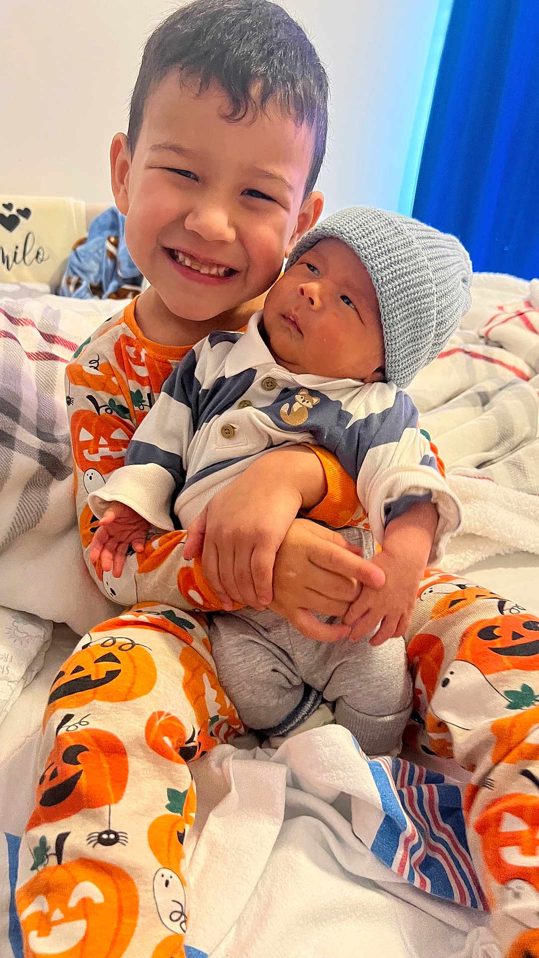 Marco Y Camilo joined the competition — help win amazing prizes! child, baby, smiling, pajamas, bed, blanket, knit_hat, sibling, holding, happy, indoor, cute, portrait, person, young_child, infant, cozy, family, toddler, sleepwear