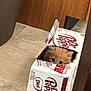 kitten, cat, cardboard_box, dr_pepper, beverage_pack, peeking, curious, tile_floor, wooden_door, indoor, pet, fur, eyes, small_animal, packaging, hole, playful, cozy, portrait, sitting