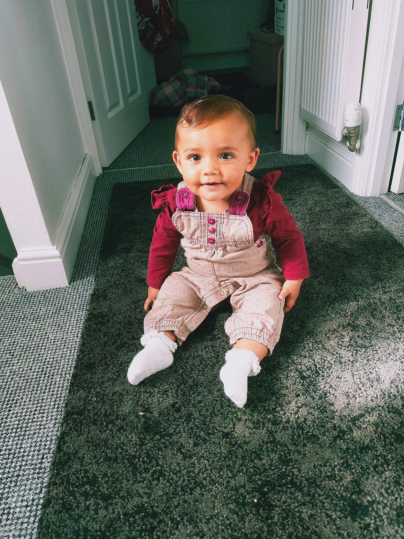 Rosianna is registered to the contest to win money with this photo: baby, baby_toddler_clothing, cheek, child, door, floor, flooring, fun, grass, hardwood, head, human_leg, joy, lawn, person, plant, room, sitting, sleeve, smile