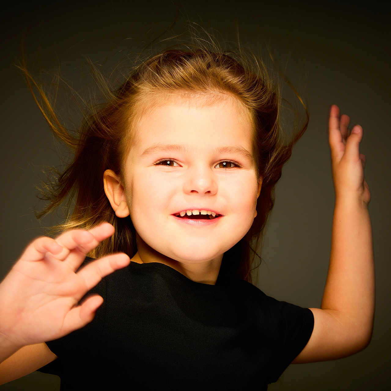 Maëlya participe au concours pour gagner de l'argent avec cette photo : arms, background, black_shirt, child, cute, expression, face, fun, girl, hair, happy, innocence, joyful, light, motion, playful, portrait, smiling, studio, young