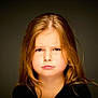 child, girl, face, portrait, expression, long_hair, brown_hair, puffed_cheeks, furrowed_brow, black_clothing, studio_lighting, isolated, closeup, emotional, cute, innocent, person, childhood, young, headshot