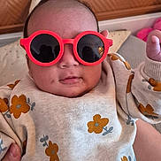 Lyianna participe au concours pour gagner de l'argent avec cette photo : baby, child, sunglasses, red, flower_pattern, clothing, hand, portrait, indoor, cute, infant, person, fashion, apparel, face, headwear, eyewear, casual, smile, baby_girl