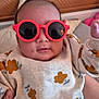 baby, child, sunglasses, red, flower_pattern, clothing, hand, portrait, indoor, cute, infant, person, fashion, apparel, face, headwear, eyewear, casual, smile, baby_girl
