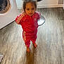 child, toddler, girl, pink_tracksuit, tracksuit, adidas_logo, bare_feet, washing_machine, kitchen_chair, window, laminate_floor, flooring, standing, looking_up, portrait, indoors, curly_hair, brown_hair, curious_expression, home_appliance
