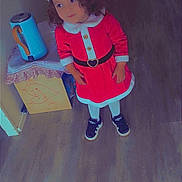 Tayana a rejoint le concours — aidez-le/la à gagner de superbes lots ! child, toddler, santa_hat, santa_costume, red_dress, curly_hair, sneakers, indoor, wooden_floor, standing, holiday, christmas, kettle, side_table, cardboard_box, drawing, portrait, cute, belt, smile