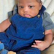 Federrell is registered to the contest to win money with this photo: baby, infant, child, blue_overalls, socks, bear_design, blanket, soft_texture, pouty_face, curly_hair, cute, indoor, comfortable, seated, small_hands, portrait, cozy, clothing, casual, resting