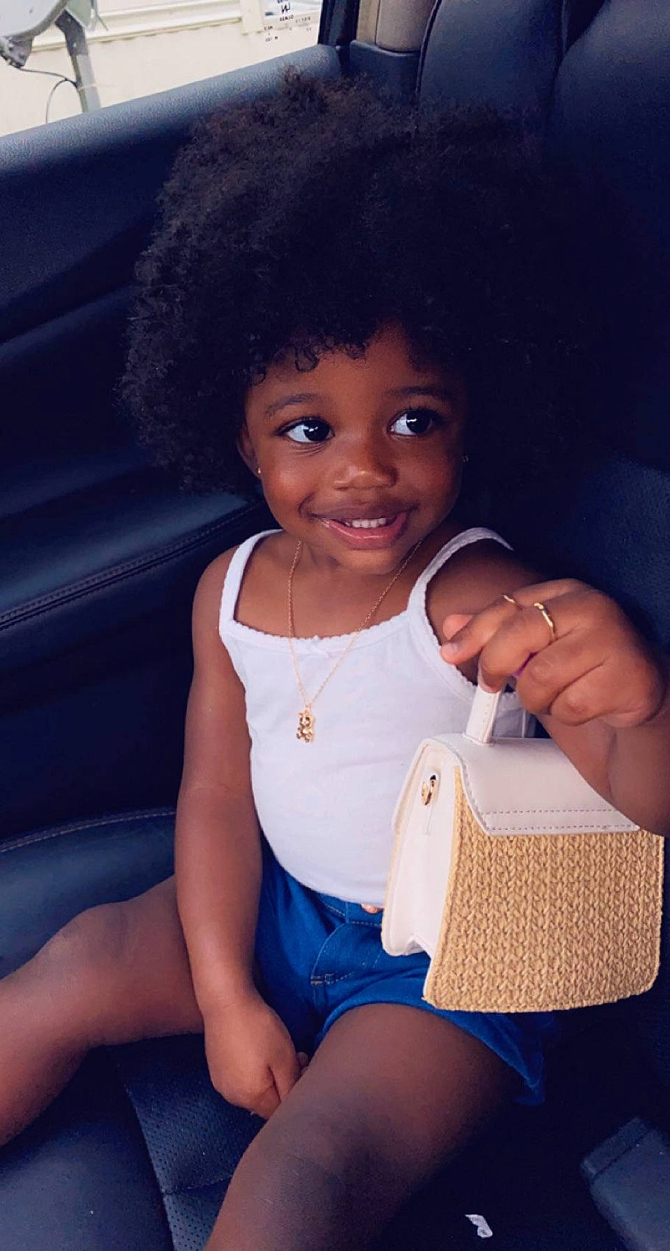 Khloe is registered to the contest to win money with this photo: afro, baby_toddler_clothing, black_hair, car_seat, child, electric_blue, finger, flash_photography, fun, happy, human_body, human_leg, joy, knee, person, sitting, skin, smile, thigh, thumb