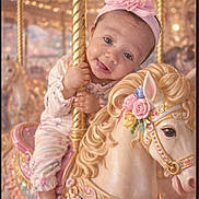 Iris joined the competition — help win amazing prizes! amusement_park, baby, carousel, carousel_horse, child, cute, decorative, festive, festivity, flower, golden_pole, happy, indoor, pastel_colors, pink_headband, playful, portrait, ride, smiling, toy_horse