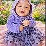 Iris is registered to the contest to win money with this photo: baby, blanket, butterfly_pattern, child, colorful, cute, dress, flowers, garden, grass, happy, hood, infant, nature, outdoor, portrait, purple_clothing, sitting, smiling, sunlight