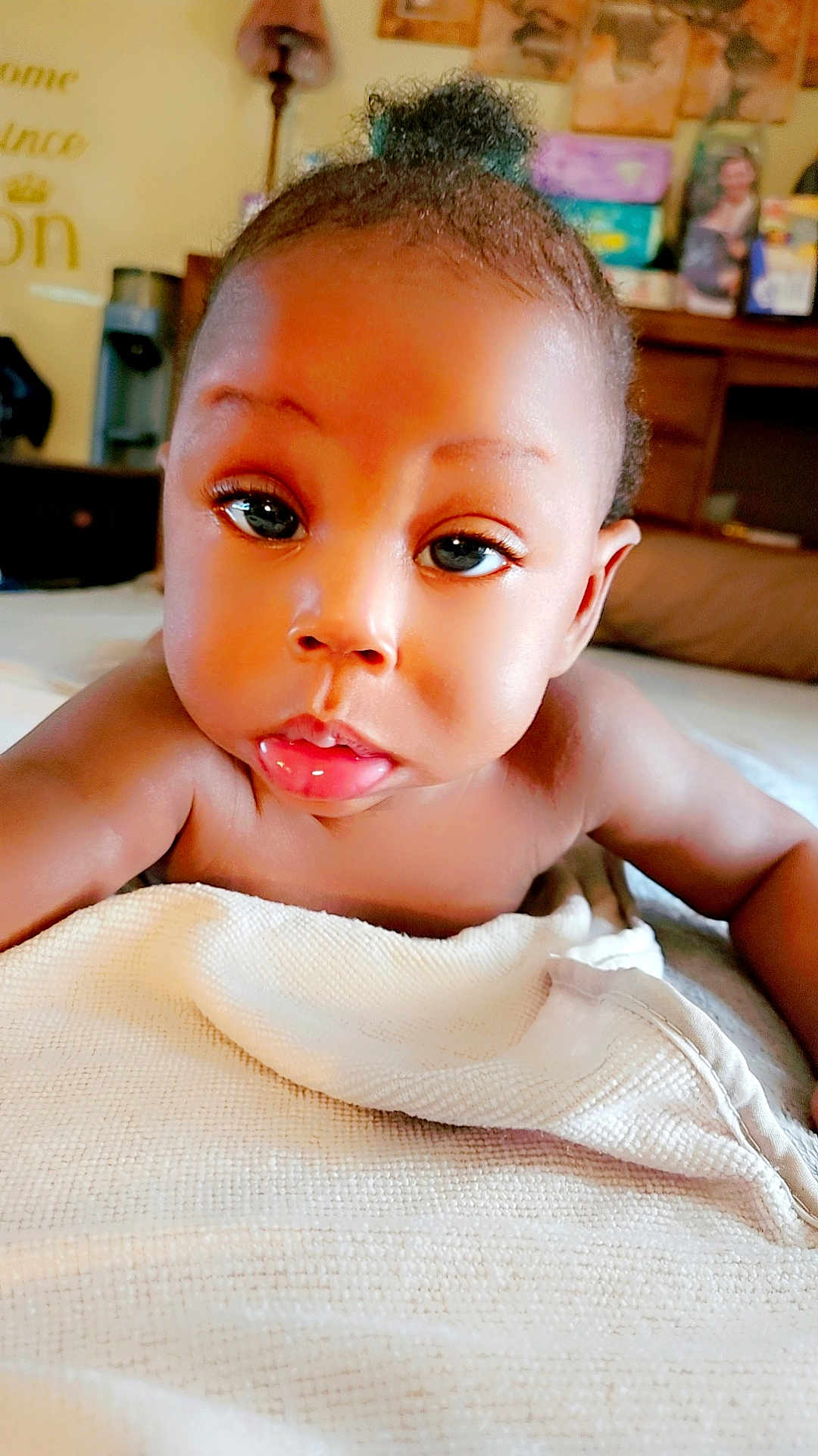 Zion is registered to the contest to win money with this photo: baby, infant, child, face, eyes, skin, blanket, drool, expression, topknot, lying_down, indoors, soft_texture, closeup, portrait, cute, curious, homedecor, furniture, warm_lighting