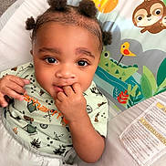 Eyad joined the competition — help win amazing prizes! baby, child, infant, cute, smiling, face, hand, fingers, hair_buns, baby_seat, colorful, cartoon_animals, giraffe, sloth, clothing, green_shirt, playful, indoors, portrait, young