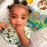 baby, child, infant, cute, smiling, face, hand, fingers, hair_buns, baby_seat, colorful, cartoon_animals, giraffe, sloth, clothing, green_shirt, playful, indoors, portrait, young