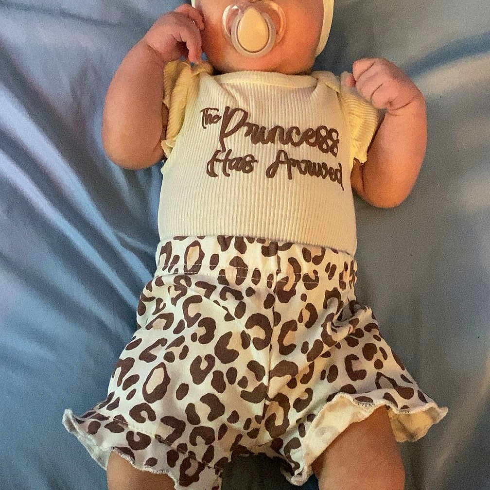 Alaura is registered to the contest to win money with this photo: baby, infant, pacifier, headband, yellow_clothing, leopard_print, shorts, socks, blanket, lying_down, cute, child, soft_lighting, indoor, portrait, small_baby, adorable, resting, young_child, person