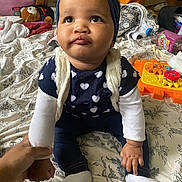 Thaïssy a rejoint le concours — aidez-le/la à gagner de superbes lots ! toddler, child, baby, headband, blue, sweater, heart_pattern, white_socks, jeans, bedspread, toy, hand, indoor, pout, cute, portrait, person, sitting, floral, holding_hand