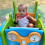 Thaïssy participe au concours pour gagner de l'argent avec cette photo : baby, child, playground, ride, colorful, outdoor, summer, cute, infant, seat, toy, park, green, blue, orange, expression, face, person, sitting, sunlight