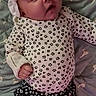 baby, infant, child, portrait, lying_down, bed, quilt, headband, bow, floral_clothing, dress, socks, indoors, face, eyes, looking_at_camera, patterned_fabric, textile, cute, family_photo