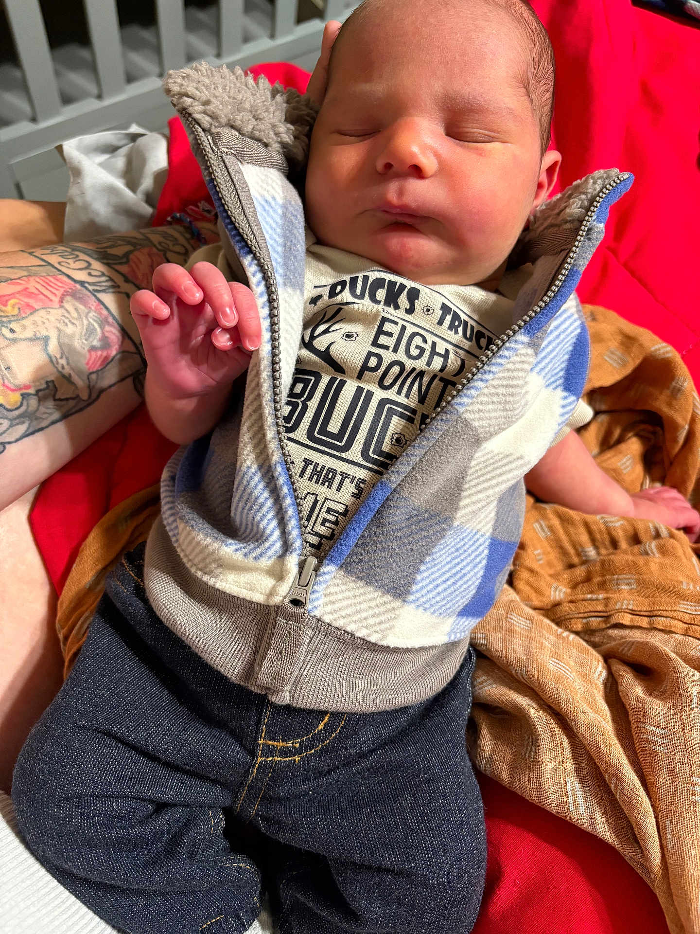 Waylon is registered to the contest to win money with this photo: baby, newborn, sleeping, clothing, tattoo, hand, blanket, jeans, vest, person, infant, soft, cozy, closeup, indoor, resting, cute, warm, fabric, skin