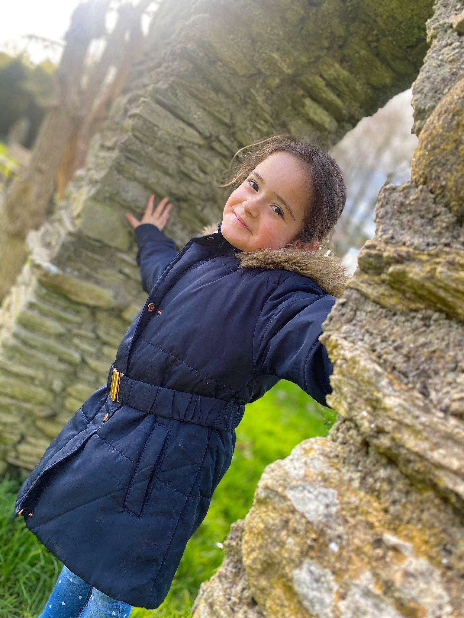Lyana participe au concours pour gagner de l'argent avec cette photo : bedrock, blond, branch, flash_photography, forest, grass, happy, jacket, joy, leisure, long_hair, outerwear, people_in_nature, person, recreation, rock, smile, tree, trunk, wall