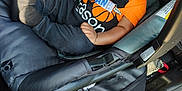 Shane is registered to the contest to win money with this photo: baby, car_seat, child, smiling, orange_shirt, black_pants, infant, seatbelt, car_interior, happy, sitting, child_safety, cute, young_child, clothing, person, portrait, daylight, seat, vehicle