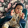 Adem a rejoint le concours — aidez-le/la à gagner de superbes lots ! baby, beanie, child, chubby_cheeks, cute, denim_jacket, dinosaur_pajamas, eyes, face, floral_wallpaper, hands, hat, indoors, infant, patterned_background, playful_expression, portrait, sitting, sock, teal_chair