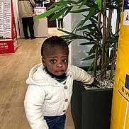 Yerim a rejoint le concours — aidez-le/la à gagner de superbes lots ! toddler, child, indoor, plant, pot, sweater, jeans, curious, exploration, people, floor, wooden_floor, leaf, green, adult, conversation, casual_clothing, standing, expression, portrait