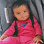 baby, black_hair, car_seat, casual_wear, child, closeup, cute, expression, face, hands, indoors, infant, person, pink_clothing, portrait, safety, seatbelt, sitting, smile, young_child