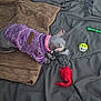 animal, bed, black_bedspread, blanket, brown_blanket, cat, cozy, curious_cat, feline, green_toy_stick, hairless_cat, indoor, pet, pet_toys, pink_collar, playing, purple_sweater, red_feather_toy, resting, yellow_white_ball