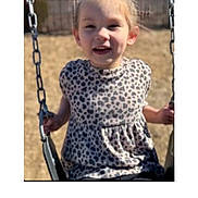 Iris is registered to the contest to win money with this photo: child, girl, swing, playground, outdoor, sunny, leopard_print, top, hair_bun, smiling, holding, metal_chains, seat, daylight, happy, young, person, casual, fun, park