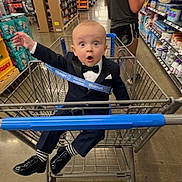 Clayton joined the competition — help win amazing prizes! baby, child, shopping_cart, supermarket, bow_tie, suit, formalwear, shoes, smiling, surprised, portrait, indoor, retail, grocery_store, aisle, walmart, shopping, cart, shelf, family