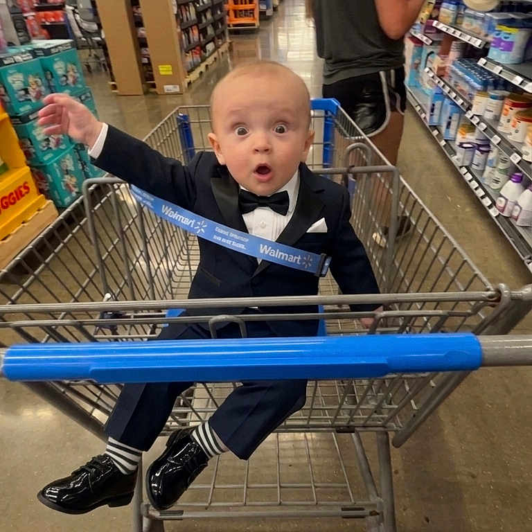 Clayton joined the competition — help win amazing prizes! baby, child, shopping_cart, supermarket, bow_tie, suit, formalwear, shoes, smiling, surprised, portrait, indoor, retail, grocery_store, aisle, walmart, shopping, cart, shelf, family