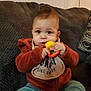 Khaled is registered to the contest to win money with this photo: baby, child, toy, couch, jacket, pants, bib, indoor, curious, seated, cozy, hands, face, cute, infant, furniture, soft, warm, expression, home