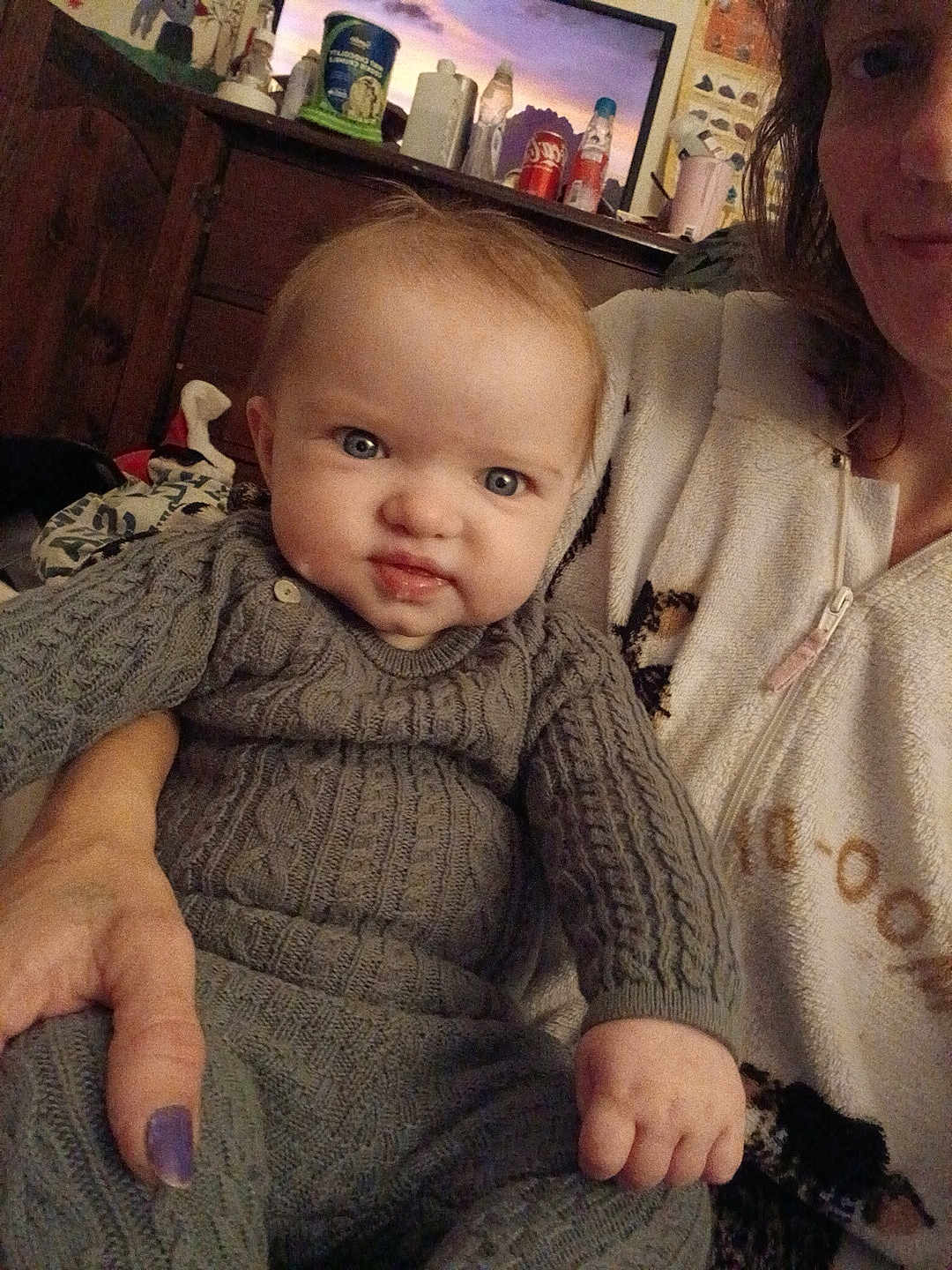 Kinsleigh is registered to the contest to win money with this photo: baby, child, person, adult, sweater, knitwear, hand, face, indoor, furniture, dresser, bottle, can, clothing, portrait, expression, holding, adult_hand, cozy, casual