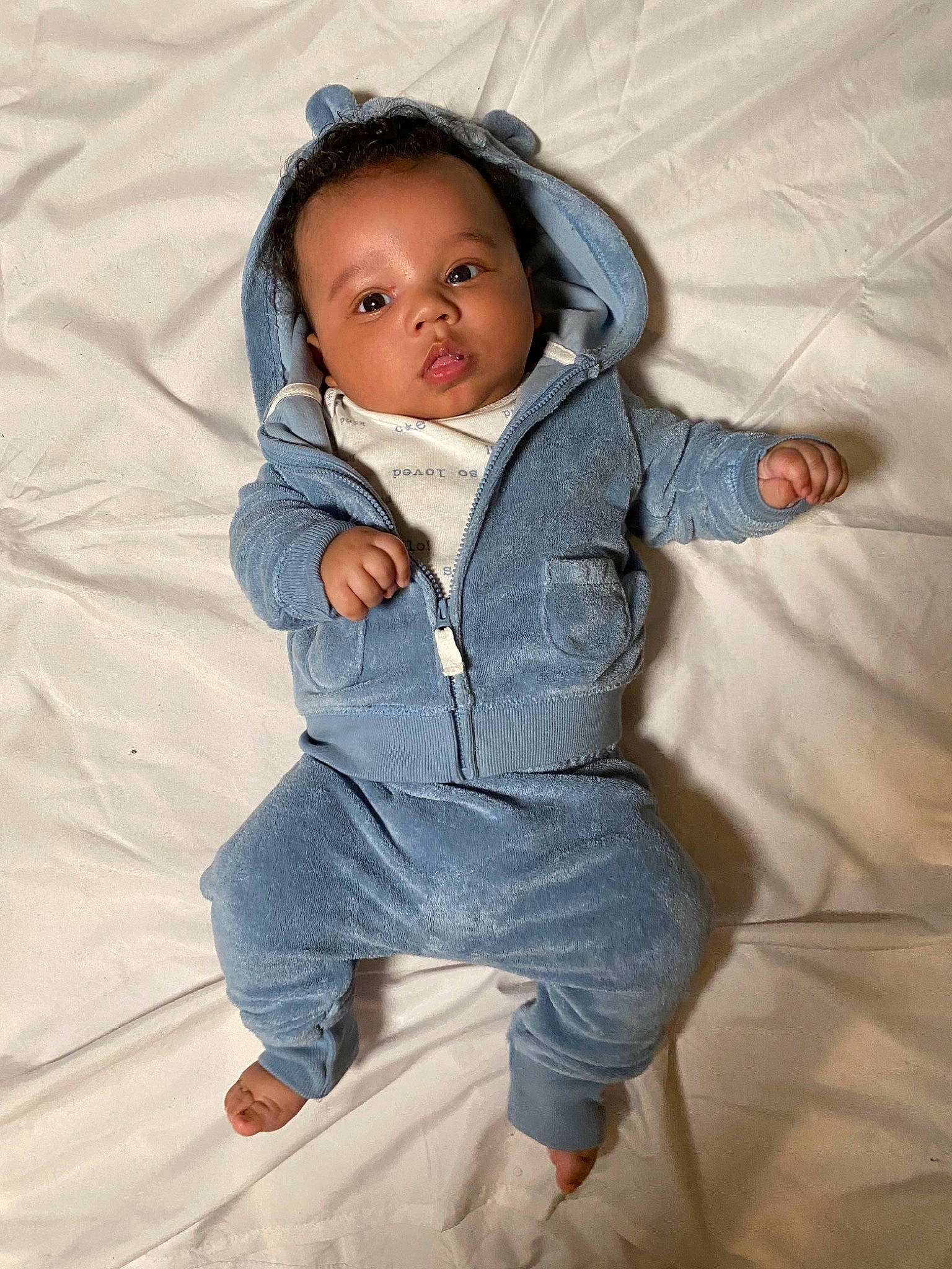 Kase is registered to the contest to win money with this photo: arm, baby, baby_toddler_clothing, cheek, child, comfort, flash_photography, fun, happy, head, human_body, jacket, linens, nose, outerwear, person, sitting, skin, sleeve, textile