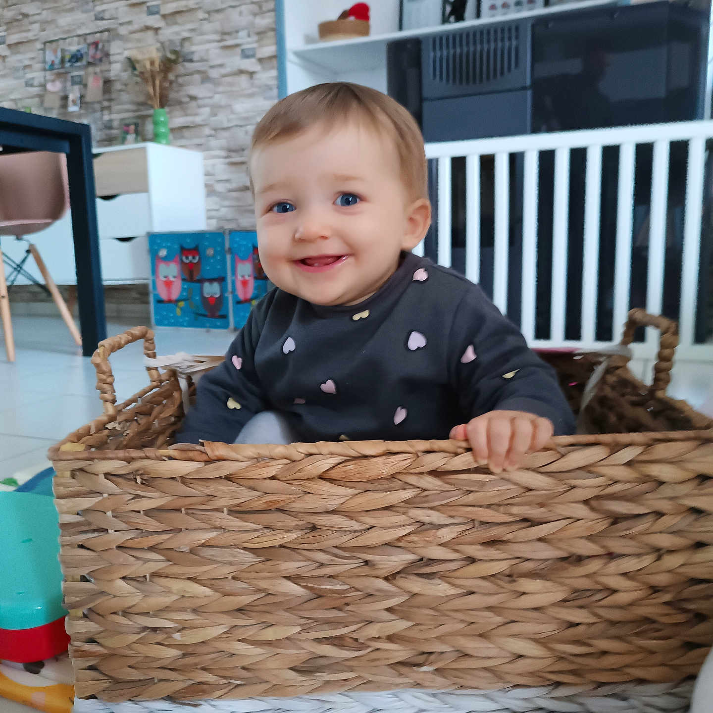 Iris participe au concours pour gagner de l'argent avec cette photo : baby, basket, blue_eyes, child, clothing, cute, decor, floor, furniture, hand, happy, home, indoor, person, playful, sitting, smiling, toddler, toy, woven