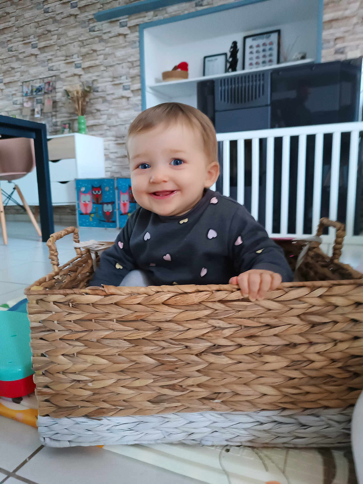 Iris participe au concours pour gagner de l'argent avec cette photo : baby, child, basket, smiling, indoor, blue_eyes, woven, furniture, toy, floor, cute, happy, person, clothing, home, decor, hand, sitting, playful, toddler