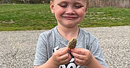 Wyatt joined the competition — help win amazing prizes! child, boy, smile, mushroom, morel, outdoor, nature, grass, trees, cloudy_sky, gravel_path, casual_clothing, shorts, tshirt, standing, happy, daylight, forest_edge, young, person