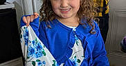 Ella is registered to the contest to win money with this photo: child, girl, smiling, bunny_ears, blue_clothing, curly_hair, indoor, kitchen, refrigerator, adult, hand, floor, door, window, patterned_clothing, person, holding, portrait, happy, casual