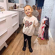 Pauline participe au concours pour gagner de l'argent avec cette photo : child, girl, smiling, bathroom, mirror, reflection, sweatshirt, hearts, leopard_print, black_pants, boots, towels, wood_floor, sink, cabinet, home_interior, standing, happy, casual_clothing, pose
