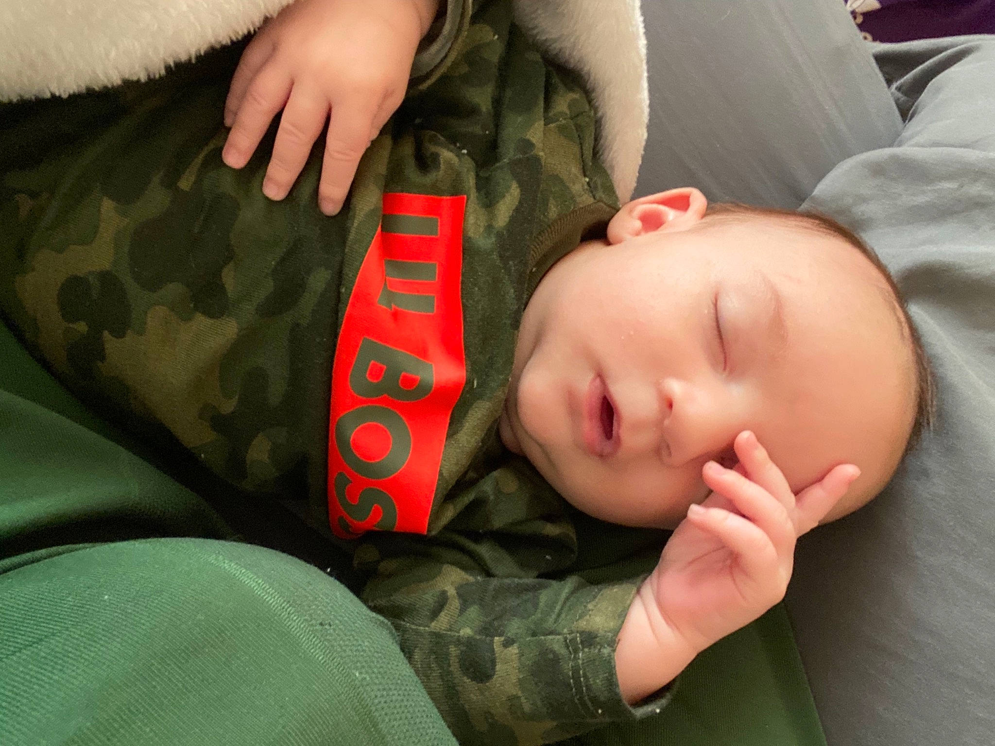 Jayce is registered to the contest to win money with this photo: baby, baby_toddler_clothing, camouflage, cheek, comfort, eye, facial_expression, finger, gesture, hand, head, human_body, joint, mammal, military_camouflage, mouth, person, skin, sleeve, toddler