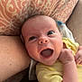 baby, infant, smiling, happy, yellow_clothing, cushion, pattern, arm, skin, face, mouth_open, indoor, closeup, person, newborn, cute, child, expression, resting, soft_lighting