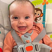 Lainey is registered to the contest to win money with this photo: baby, baby_seat, blue_eyes, cheerful, child, child_seat, closeup, cute, elephant_patch, face, happy, indoors, infant, monkey, orange_clothing, playful, safety_harness, seatbelt, smiling, toy_pattern
