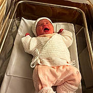 Mïa participe au concours pour gagner de l'argent avec cette photo : baby, bassinet, blanket, cozy, cute, hat, hospital, indoors, infant, knitted_clothes, lying_down, medical_equipment, newborn, person, pink_pants, portrait, sleeping, socks, soft_lighting, white_sweater