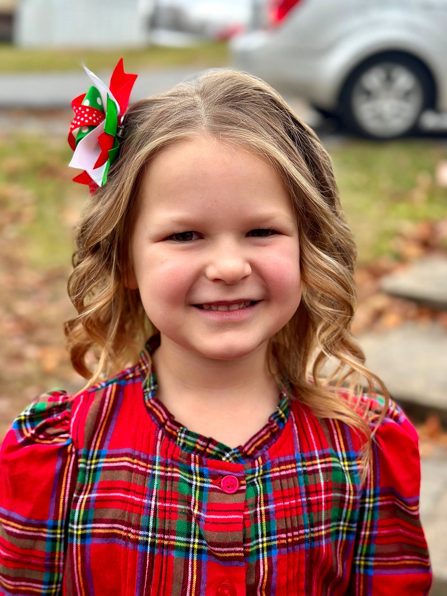 Harley is registered to the contest to win money with this photo: automotive_tire, beauty, car, child, facial_expression, grass, green, happy, joy, party_hat, pattern, people, person, photograph, plaid, red, sleeve, smile, tartan, tire
