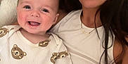 Joey joined the competition — help win amazing prizes! baby, woman, smile, couch, indoor, long_hair, onesie, bear_pattern, happy, person, child, portrait, casual_clothing, skin, head, face, seated, home, cozy, family