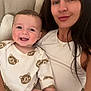baby, woman, smile, couch, indoor, long_hair, onesie, bear_pattern, happy, person, child, portrait, casual_clothing, skin, head, face, seated, home, cozy, family