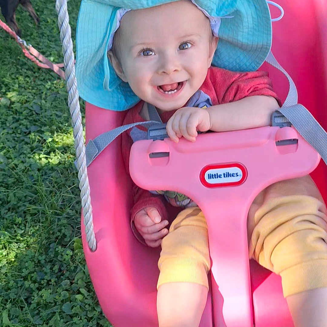 Maddox joined the competition — help win amazing prizes! baby, child, infant, smiling, happy, outdoor, swing, playground, sun_hat, pink_seat, safety_bar, grass, garden, portrait, face, hands, feet, colorful_clothing, summer, joy