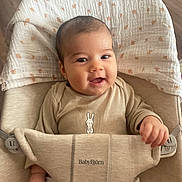 Ada a rejoint le concours — aidez-le/la à gagner de superbes lots ! baby, smile, infant, face, clothing, onesie, babybjorn, seat, child, hand, blanket, wooden_floor, happy, cute, young_child, indoors, portrait, sitting, baby_seat, comfort