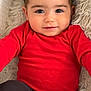 baby, black_pants, child, close_up, cozy, cute, eyes, face, fluffy_blanket, happy, indoors, infant, person, portrait, red_sweater, sitting, smiling, soft_texture, warm_clothing, young_child
