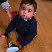 Sohan participe au concours pour gagner de l'argent avec cette photo : toddler, child, indoor, floor, wooden_floor, clothing, sweater, pants, shoes, hand, bracelets, person, portrait, young_child, casual, cute, baby, sitting, looking_at_camera, expression
